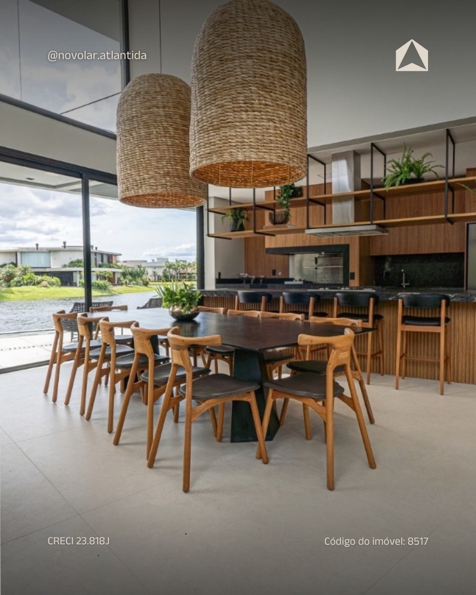 Cozinha e sala de jantar integradas, com luminárias de palha e vista para o lago